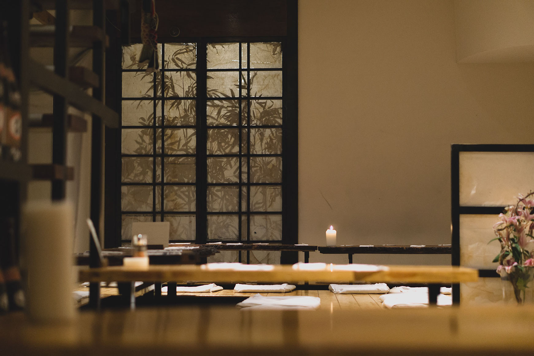 The dining room at Little Tokyo Leeds — sycamore plank tables, candles, and a shoji screen